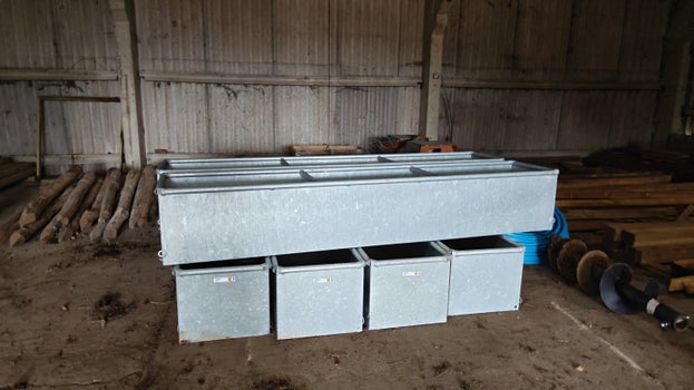 Image of large animal drinking troughs stacked in the barn awaiting installation